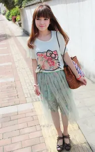 Dettaglio di una borsa a tracolla intrecciata con top giallo e gonna di tulle verde