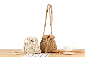 Detail of handmade crochet cotton rope bucket bags with floral patterns in cream and brown