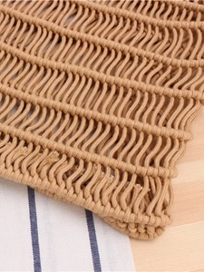 Bohemian style woven cotton rope tote bag with natural wavy texture on wooden surface