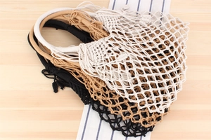 Detail of hand-woven cotton rope mesh bags in white, coffee, and black with macrame knots