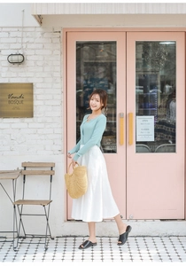 Detail of a handmade natural straw handbag paired with a mint green knit top and white skirt