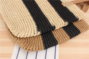 Close-up of striped woven straw handbags with brown leather handles on wooden background