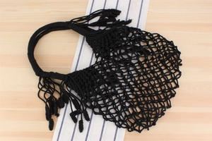 Detail of a black hand-woven cotton net bag featuring long fringes and mesh texture