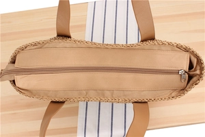 Detail of khaki woven paper rope tote bag showing zipper closure and leather handle