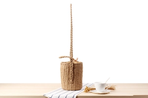Close-up of handmade paper rope woven bucket bag on a wooden table with summer decor