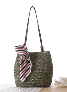 Borsa tote in paglia intrecciata verde con manici in pelle e foulard a righe su legno