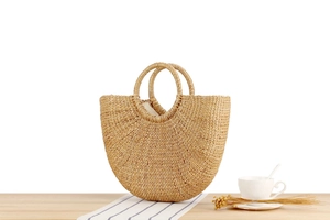 Detail of handmade straw handbag with semi-circular woven handles and fabric lining