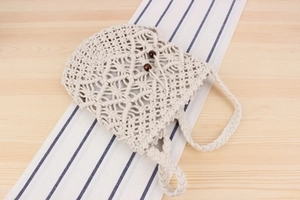 Close-up of handmade off-white macrame bag featuring bohemian woven patterns and wooden beads