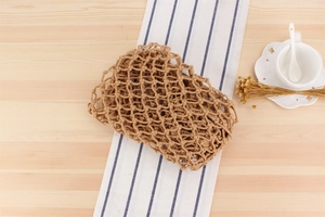 Detail of handcrafted brown woven cotton rope bag with boho tassels on a wooden surface