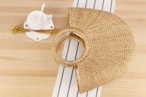 Detail of a handmade semi-circular woven straw handbag with dual circular handles