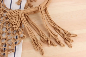 Macro detail of handmade woven cotton rope textures and bohemian tassel fringes on the bag