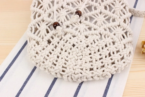 Detailed macro view of handmade cotton crochet pouch with drawstring and brown wood beads