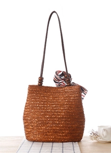 Dettaglio borsa in paglia intrecciata con perline di legno e sciarpa a righe decorativa