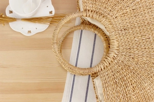 Detailed top view of handmade round straw bag with dual woven handles and fabric lining