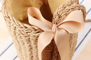 Detail of handwoven paper rope bag with apricot ribbon bow and yellow fabric lining