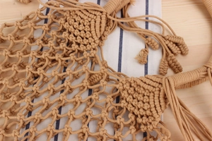 Close-up of macrame woven texture and tassel details on a camel cotton net beach bag