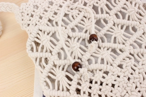 Close-up of handmade hollow star-pattern woven bag with drawstring and wooden beads
