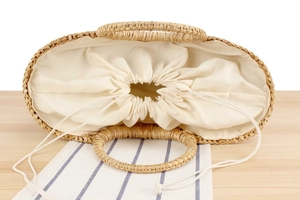 Macro detail of natural straw basket bag featuring sturdy round handles and drawstring closure