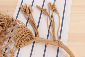 Close-up of bohemian hand-woven beige cotton rope bag with fringe tassels and texture