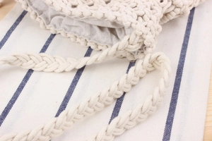 Close-up of handmade beige crochet bag featuring detailed woven texture and braided strap