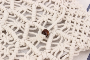 Detail of handcrafted bohemian woven bag with intricate knot patterns and a dark wooden bead