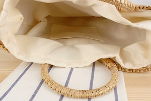 Top view of handmade straw handbag interior featuring cream fabric lining and inner pocket
