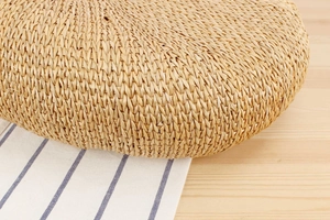 Close-up of thick round natural straw woven cushion with detailed herbal texture