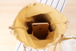 Interior detail of straw bucket bag with yellow lining showing spacious capacity for a phone