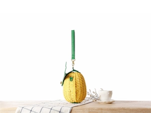 Détail du sac en paille en forme d'ananas avec texture jaune et rabat en feuilles vertes