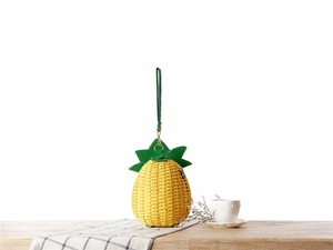 Détails du sac en paille tressée ananas avec feuilles en similicuir vert sur la table