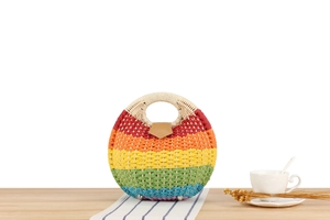 Detail of a handmade rainbow straw bag with light round handles and leather clasp detail
