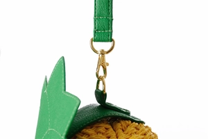 Détail du sac en paille ananas montrant la bandoulière en cuir vert et les boucles dorées