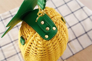 Détail du sac en paille ananas jaune avec feuilles en cuir vert et rivets dorés