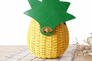 Détail d'un sac en paille en forme d'ananas avec couvercle en feuilles vertes et fermoir