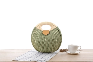 Detail view of a green handmade woven straw handbag with a brown leather buckle closure
