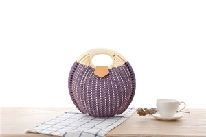 Macro detail of purple paper rope weave texture and white handle on round fashion handbag