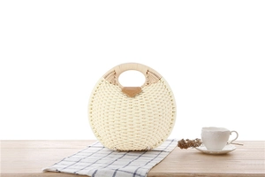 Detailed macro of a woven cream shell-shaped straw handbag with brown leather strap detail