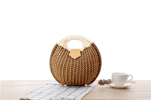 Detail of round straw handbag featuring woven texture and brown leather magnetic clasp