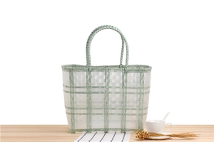 Close-up of a large green plaid waterproof woven tote bag on a picnic wooden table
