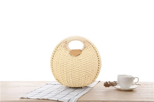 Detail of round straw handbag with brown leather flap on a checkered tablecloth