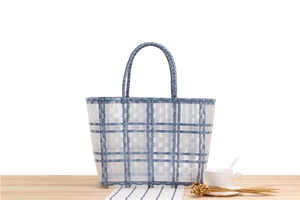 Detail of blue and white checkered woven beach bag on a table with leisure setting