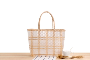 Close-up of a large woven tote bag with a checkered pattern and round handles on a wood table
