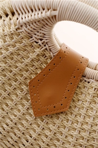 Detailed macro view of tight paper rope weaving and brown leather accent on a shell bag