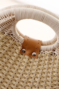 Close-up of shell-shaped woven handbag featuring natural fiber texture and leather rivet detail
