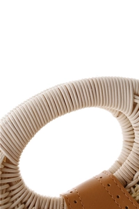 Detail of woven shell handbag featuring spiral raffia handles and brown leather stitching