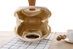 Top view of woven shell-shaped straw handbag with interior fabric lining and brown leather snap