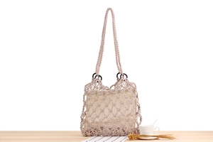 Detail of hollow woven cotton rope bag with wooden handle and inner pouch on wooden table