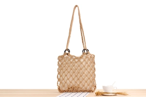 Detail of hand-woven cotton mesh beach bag with wooden rings and beige fabric lining