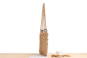 Detail of hand-woven cotton rope mesh bag with wooden rings on a rustic table