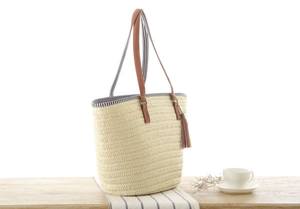 Close-up of woven straw tote bag with brown leather tassels and blue striped canvas lining